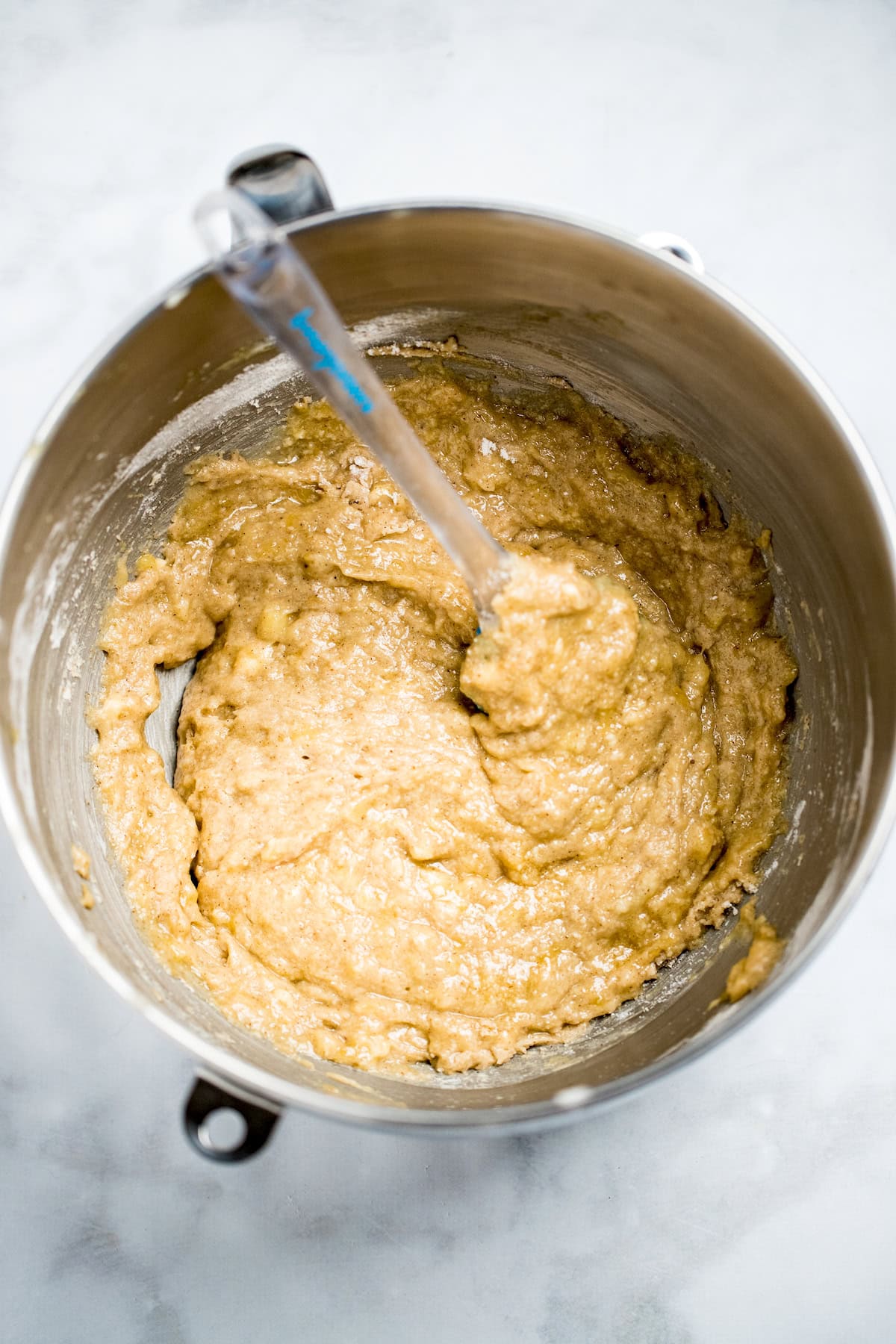 A mixing bowl with a silicon spatula mixing banana bread batter.