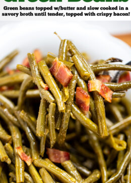 Pinterest pin with a bowl of crockpot green beans on a table, with a spoon lifting up a scoop of green beans topped with bacon.