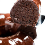 A piece of cake being lifted up from the chocolate brownie bundt cake.