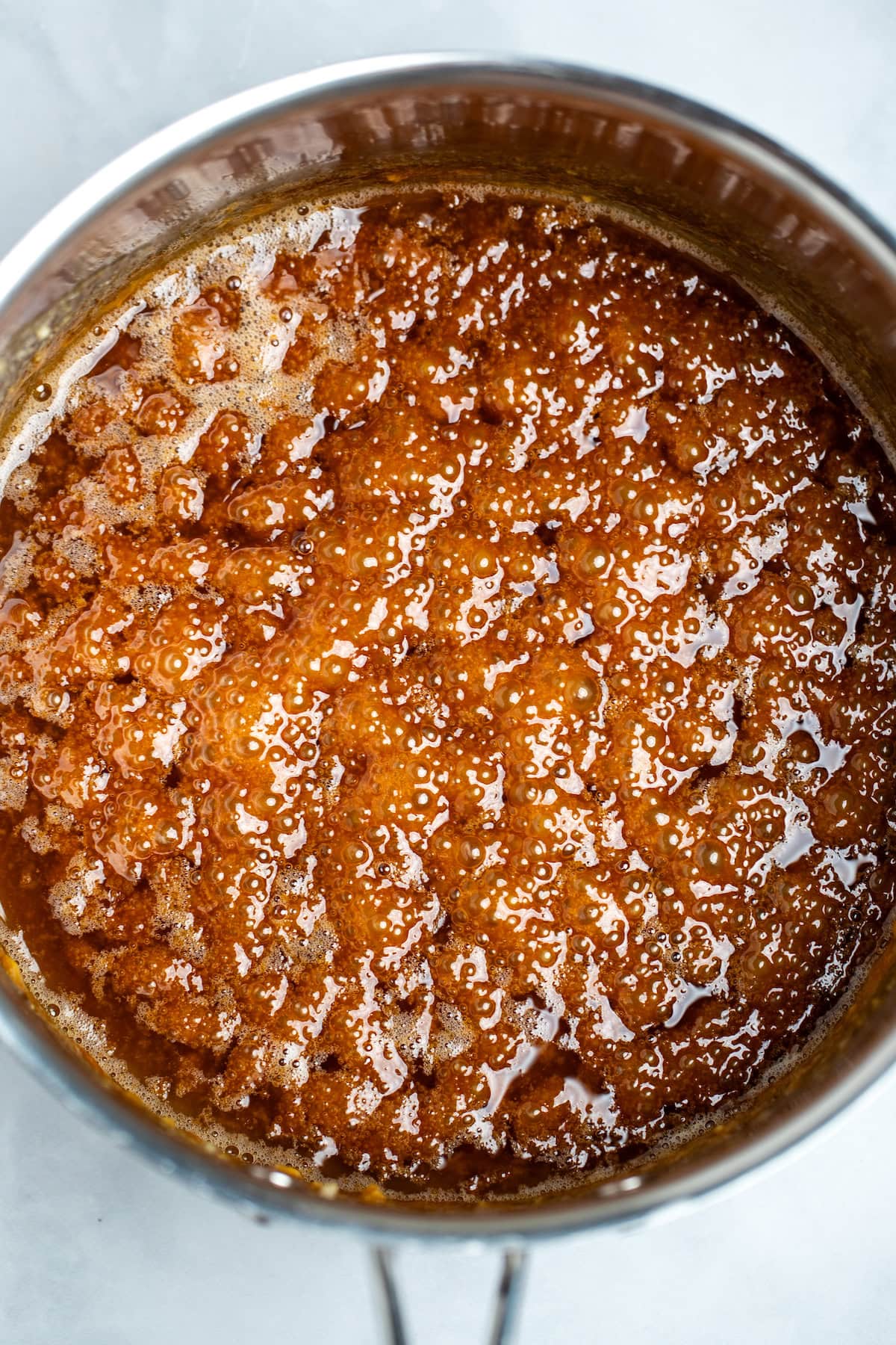 A saucepan with caramelized sugar and butter, with bubbles caused by adding the butter on top.