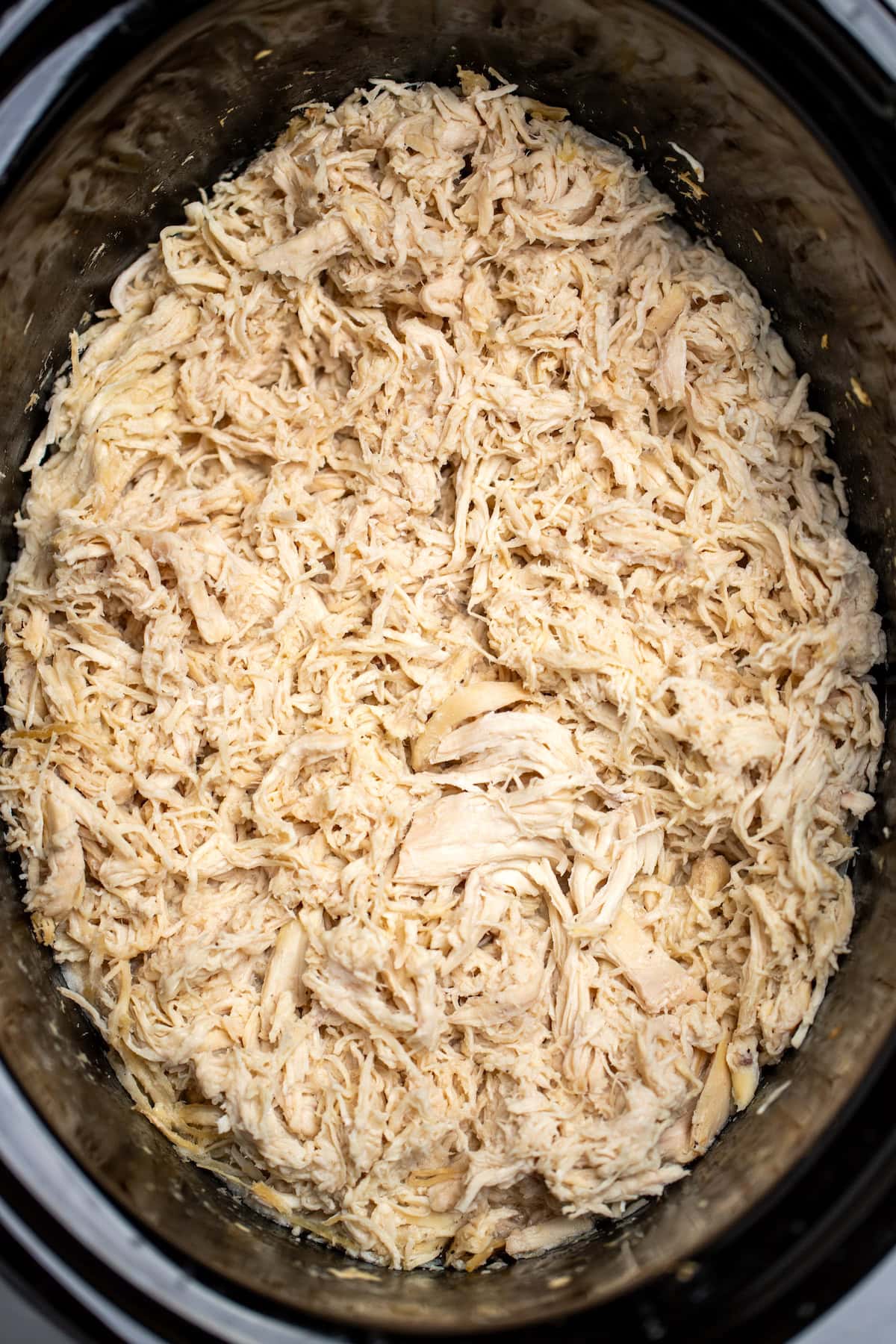 A slow cooker full of shredded chicken.