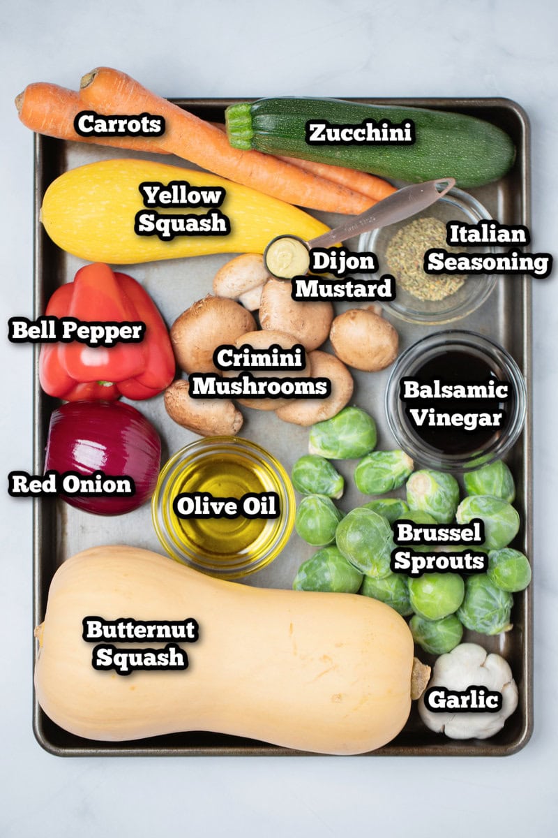 Individual ingredients for oven roasted vegetables on a sheet pan on a table.