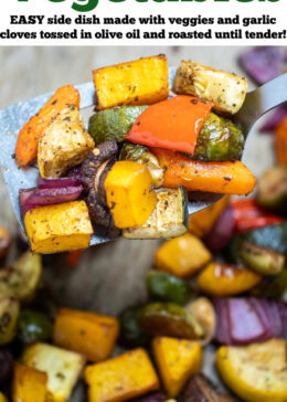 Pinterest pin with roasted vegetables on top of parchment paper on a sheet pan, with a spatula in the middle lifting some vegetables up, just out of the oven.