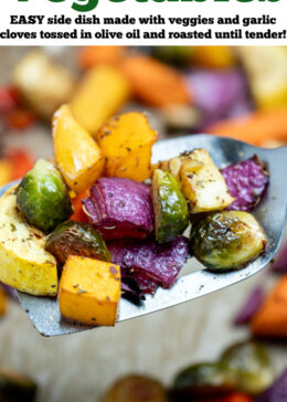 Pinterest pin with roasted vegetables on top of parchment paper on a sheet pan, with a spatula in the middle lifting some vegetables up, just out of the oven.