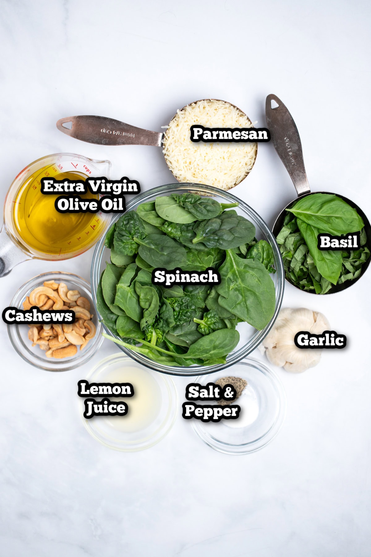 Individual ingredients for spinach pesto on a table.