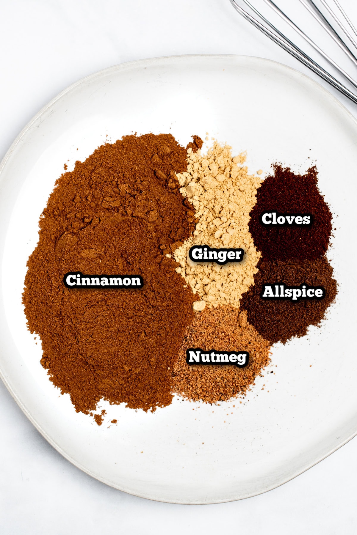 Individual ingredients for homemade pumpkin pie spice on a plate.