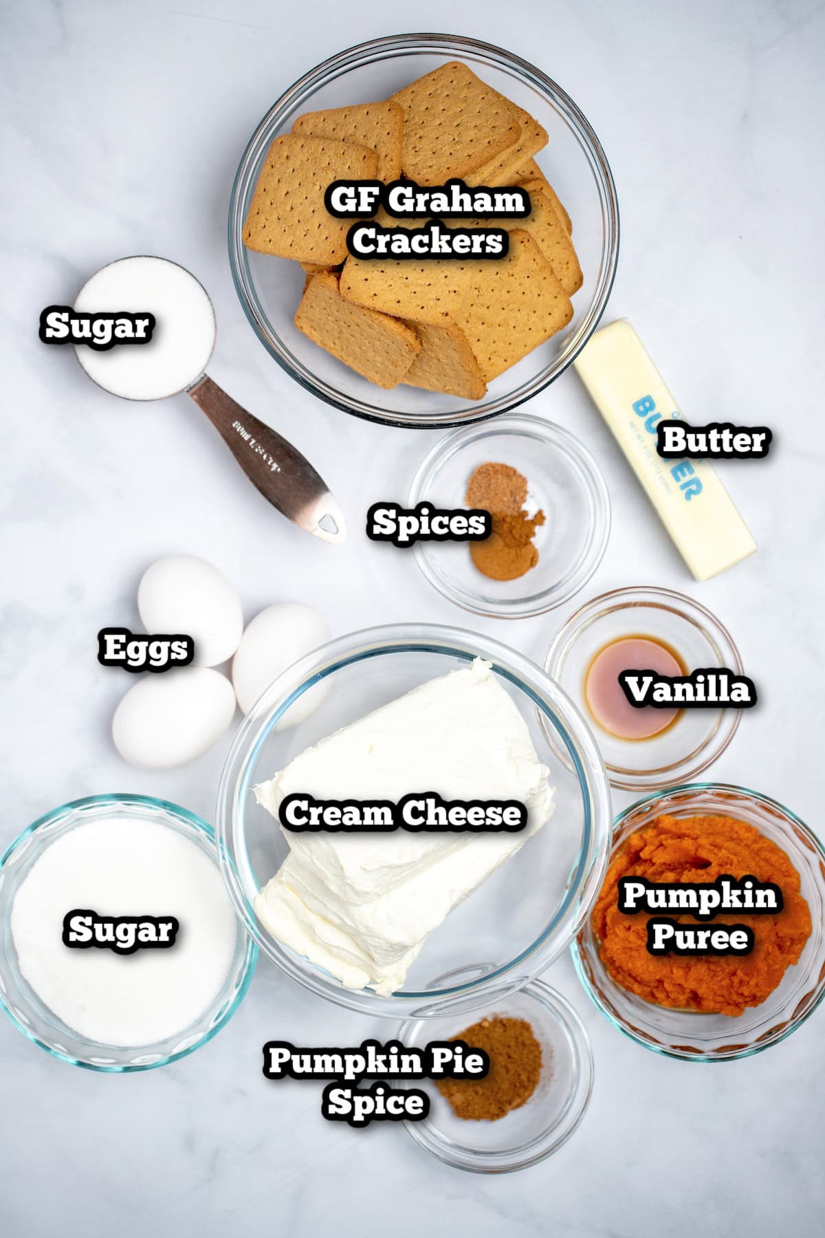 Individual ingredients for pumpkin cheesecake on a table.