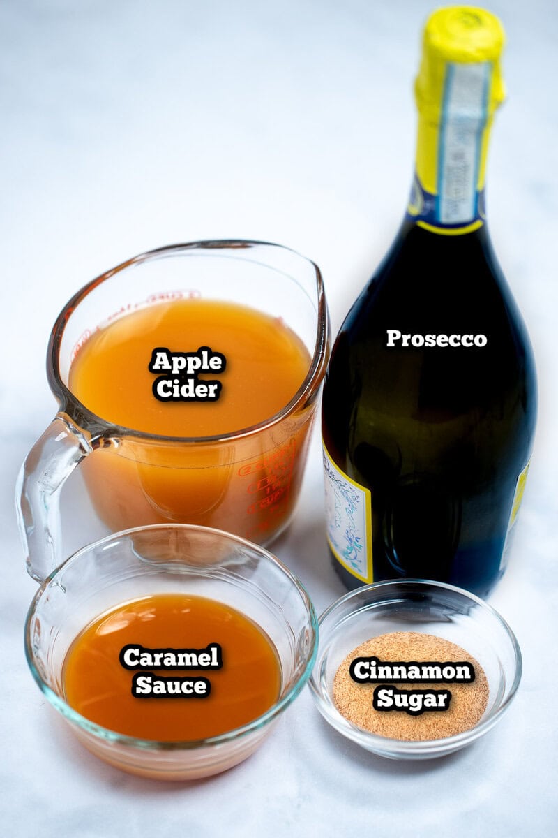 Individual ingredients for apple cider mimosas on a table.