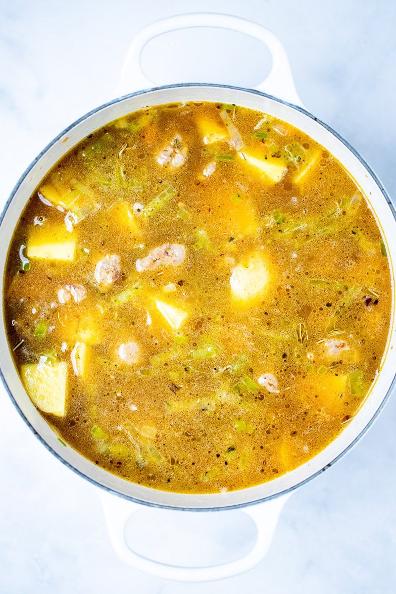 A dutch oven with potato and sausage soup before being simmered.