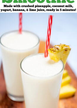 Pinterest pin with a tall glass with a pineapple wedge garnish and a straw, full of pina colada smoothie, with another glass behind it, on a cutting board with pineapple and lime wedges.