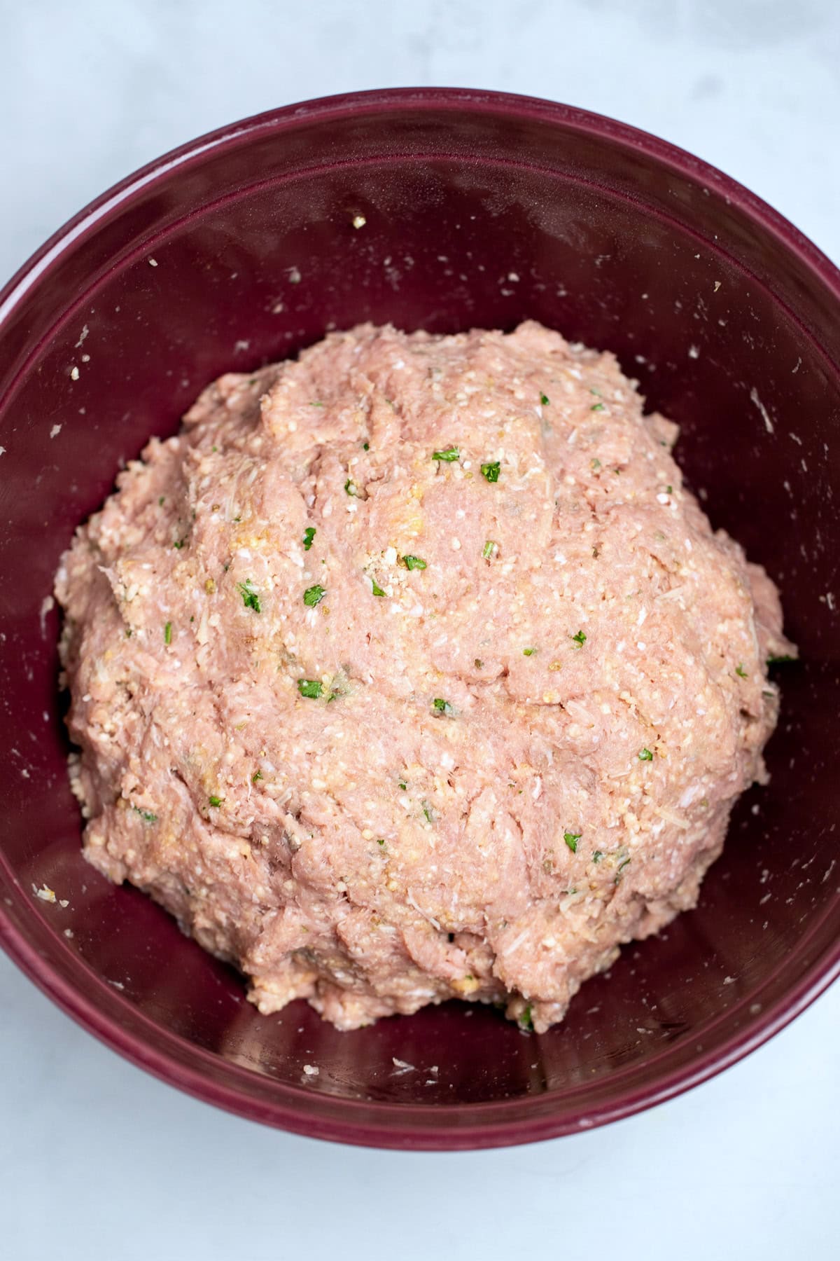 A mixing bowl on a table with meatball mixture before making meatballs.