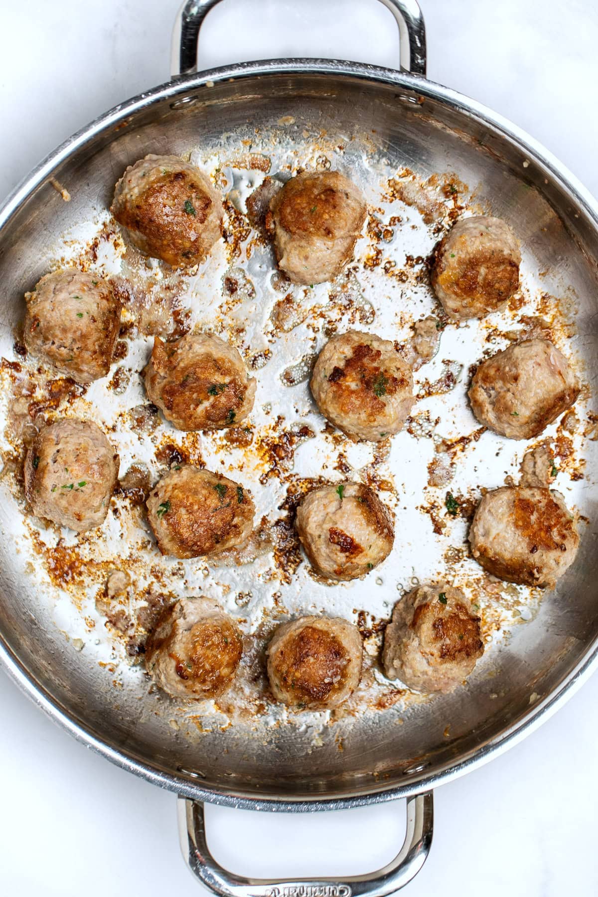 A large skillet with browned meatballs.