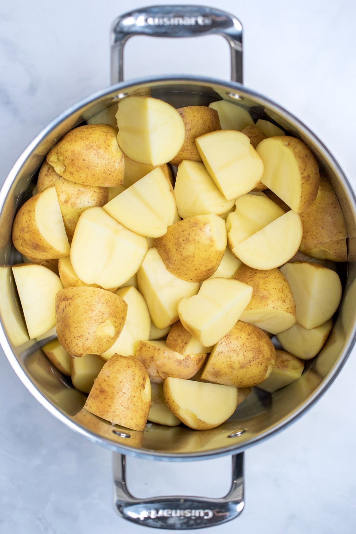 A stockpot full of quartered gold potatoes ready to be boiled.