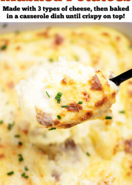 Pinterest pin with a casserole dish full of twice baked mashed potatoes with caramelized cheese on top with fresh chopped chives, with a spoon lifting some mashed potatoes up.