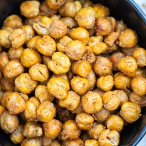 A bowl on a table with crispy air fryer chickpeas coated in seasoning.