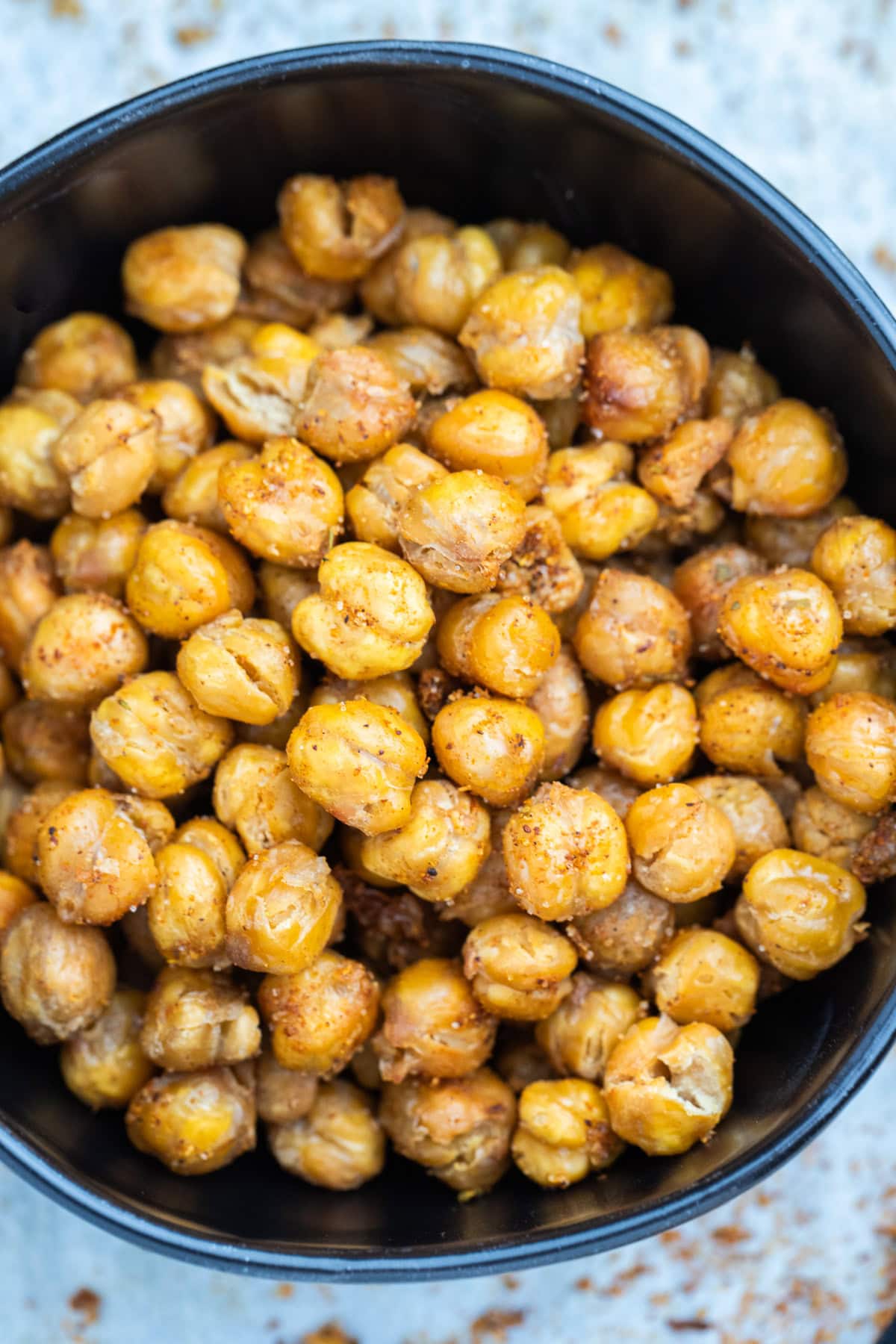 A bowl on a table with crispy air fryer chickpeas coated in seasoning.