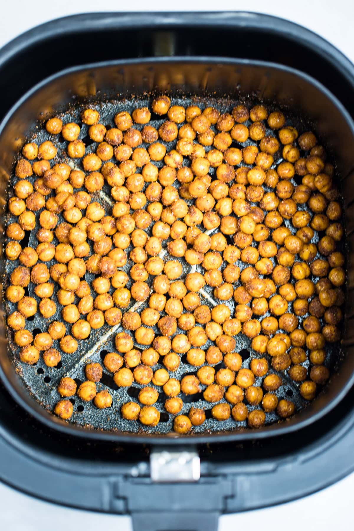 An air fryer basket with crispy air fried chickpeas in a single layer.