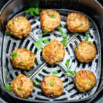 Air fryer turkey meatballs in an air fryer basket after being cooked. They're brown and caramelized and topped with fresh parsley.