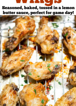 Pinterest pin with a sheet pan lined with tinfoil and a baking rack with cooked lemon pepper chicken wings topped with fresh parsley.