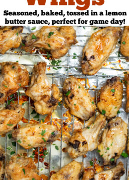 Pinterest pin with a sheet pan lined with tinfoil and a baking rack with cooked lemon pepper chicken wings topped with fresh parsley.