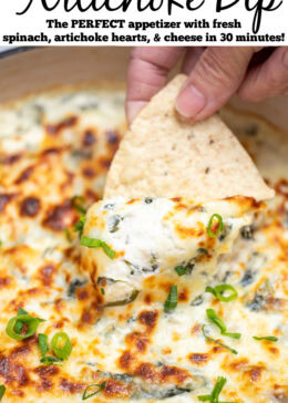 Pinterest pin with a dutch oven full of spinach artichoke dip with a caramelized top, topped with chopped green onions, with a hand holding a tortilla chip scooping up some dip.