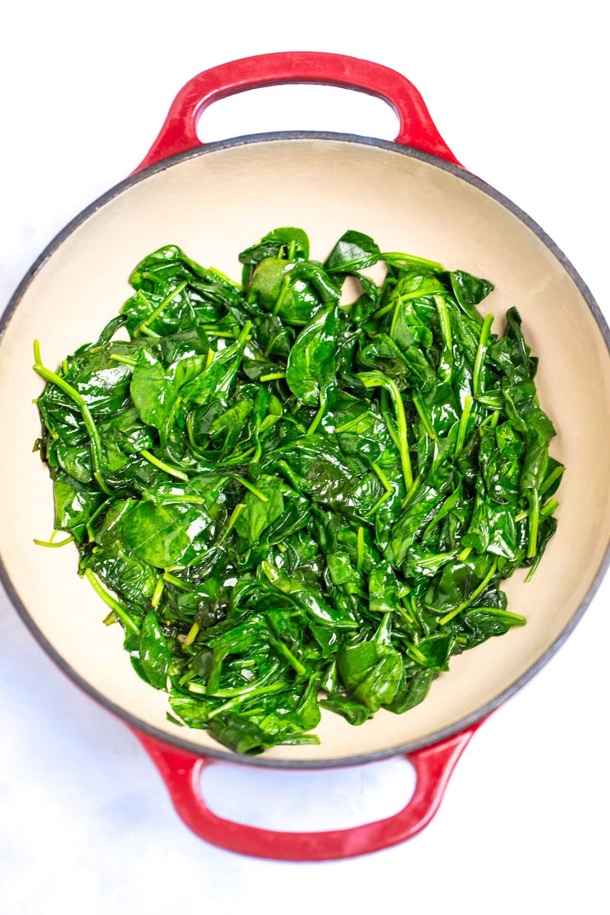 A dutch oven full of cooked spinach.