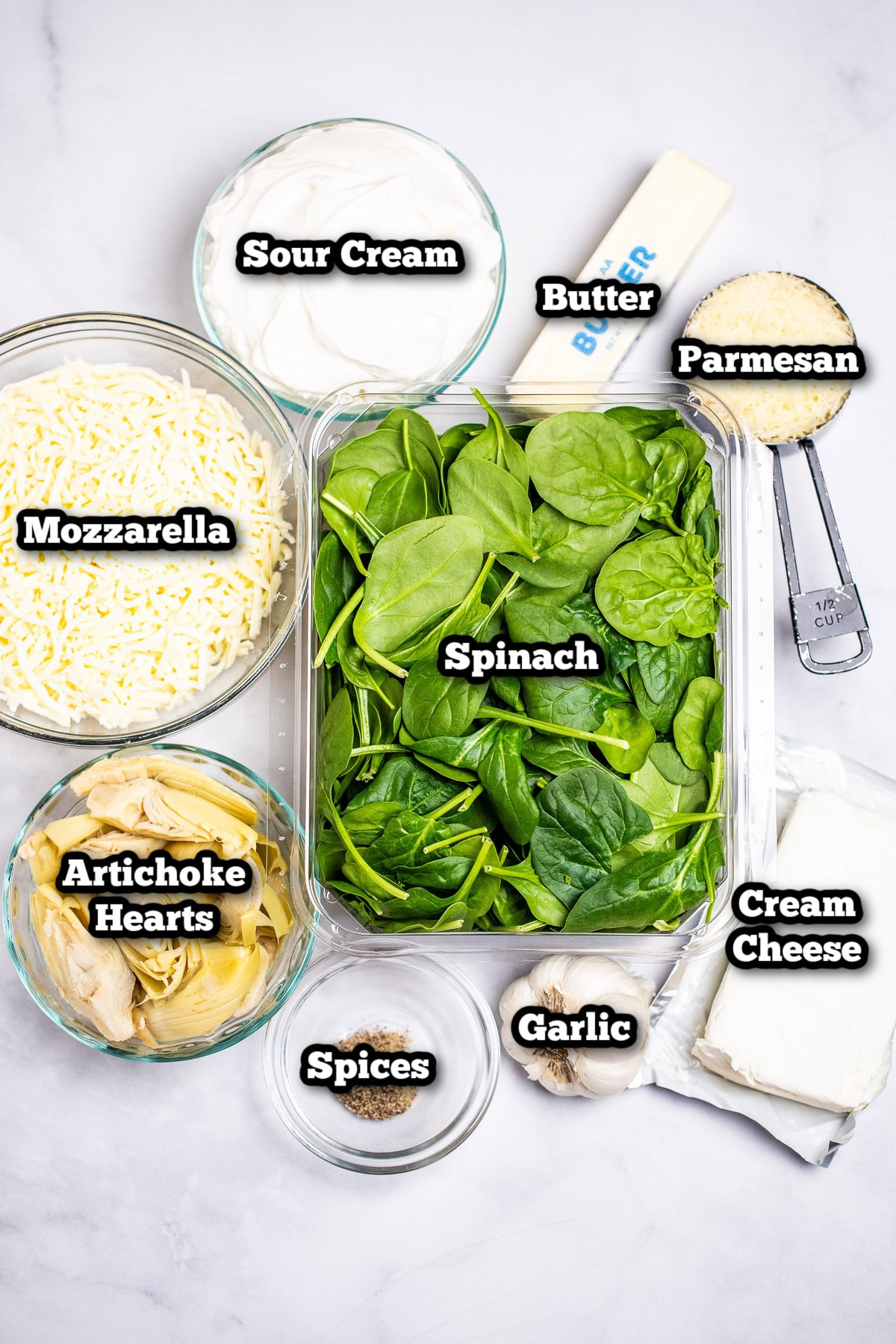 Individual ingredients for spinach artichoke dip on a table.