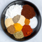 A bowl on a table with each spice for fajita seasoning in its own spot in the bowl.