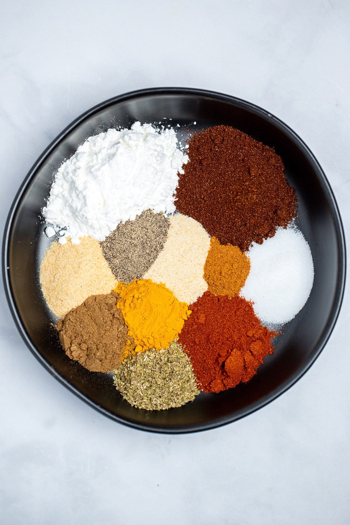 A bowl on a table with each spice for fajita seasoning in its own spot in the bowl.