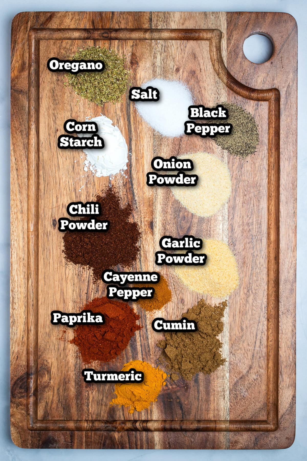 Individual spices for homemade fajita seasoning on a cutting board on a table.