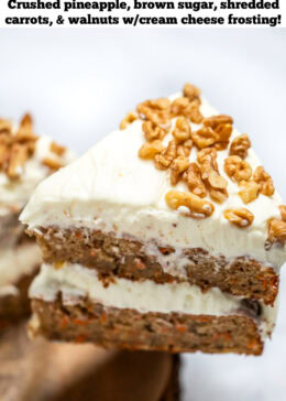 Pinterest pin with a double layer carrot cake on a wooden cake plate, with a layer of cream cheese frosting in the middle and on top, with walnuts around the edges of the top of the cake. There is a piece of cake being lifted away from the cake.