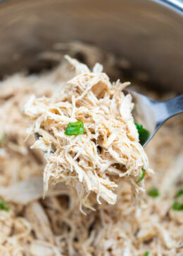 Pinterest pin with an instant pot with shredded chicken breast topped with fresh chopped green onions, with a spoon lifting some up above the pot.