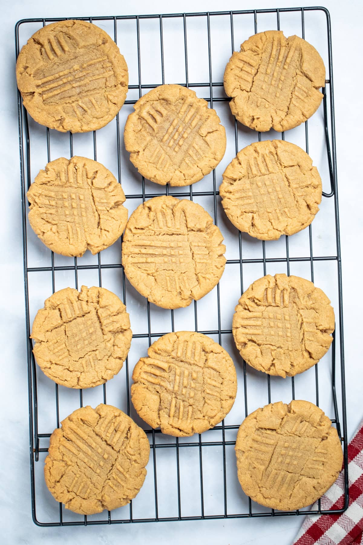 A cookie rack on a table with gluten free peanut butter cookies cooling.