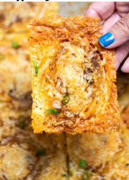 Pinterest pin with a hand holding an onion ring chip over a sheet pan of more chips topped with chopped green onion.